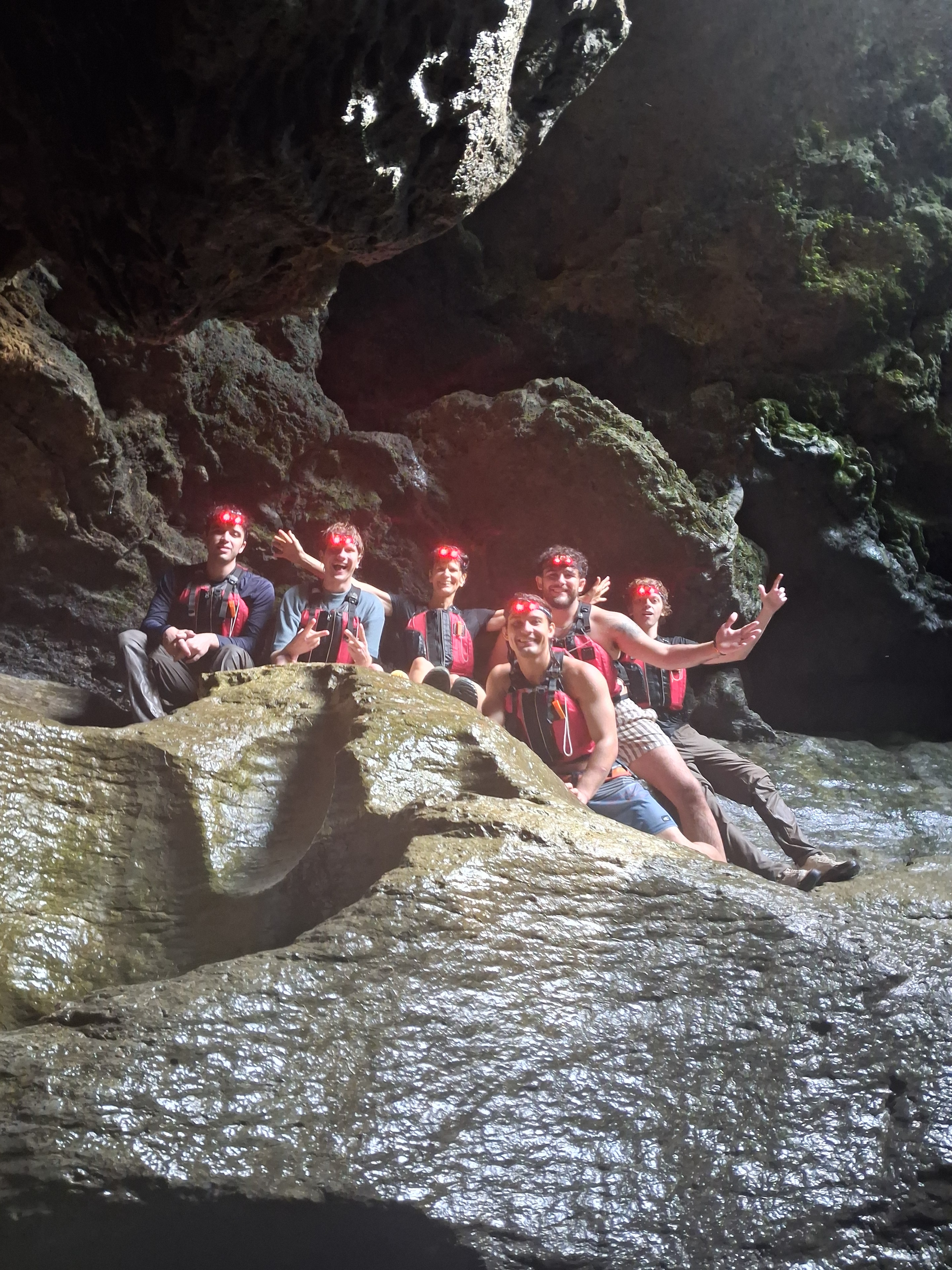 Group of four hikers posing inside a karst cave at Charco Azul