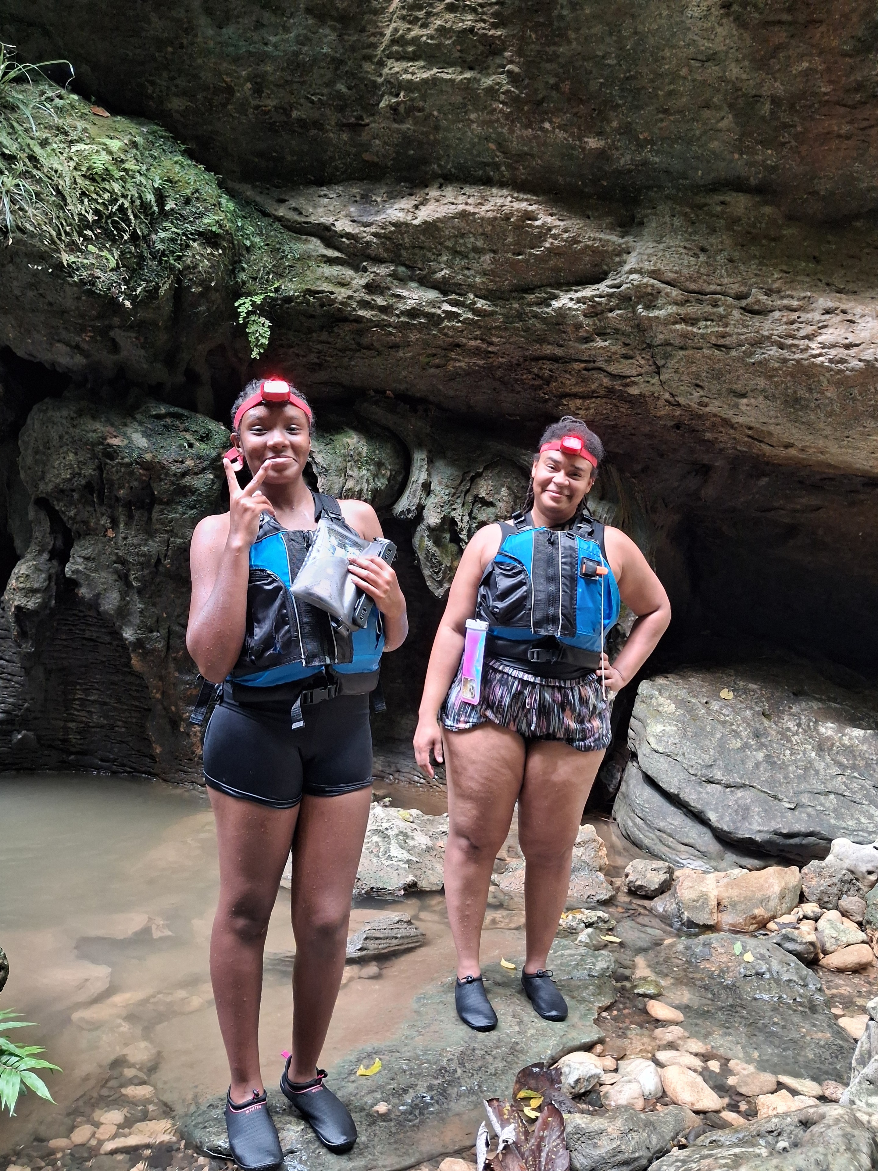 Two guests in life vests smiling at the cave entrance
