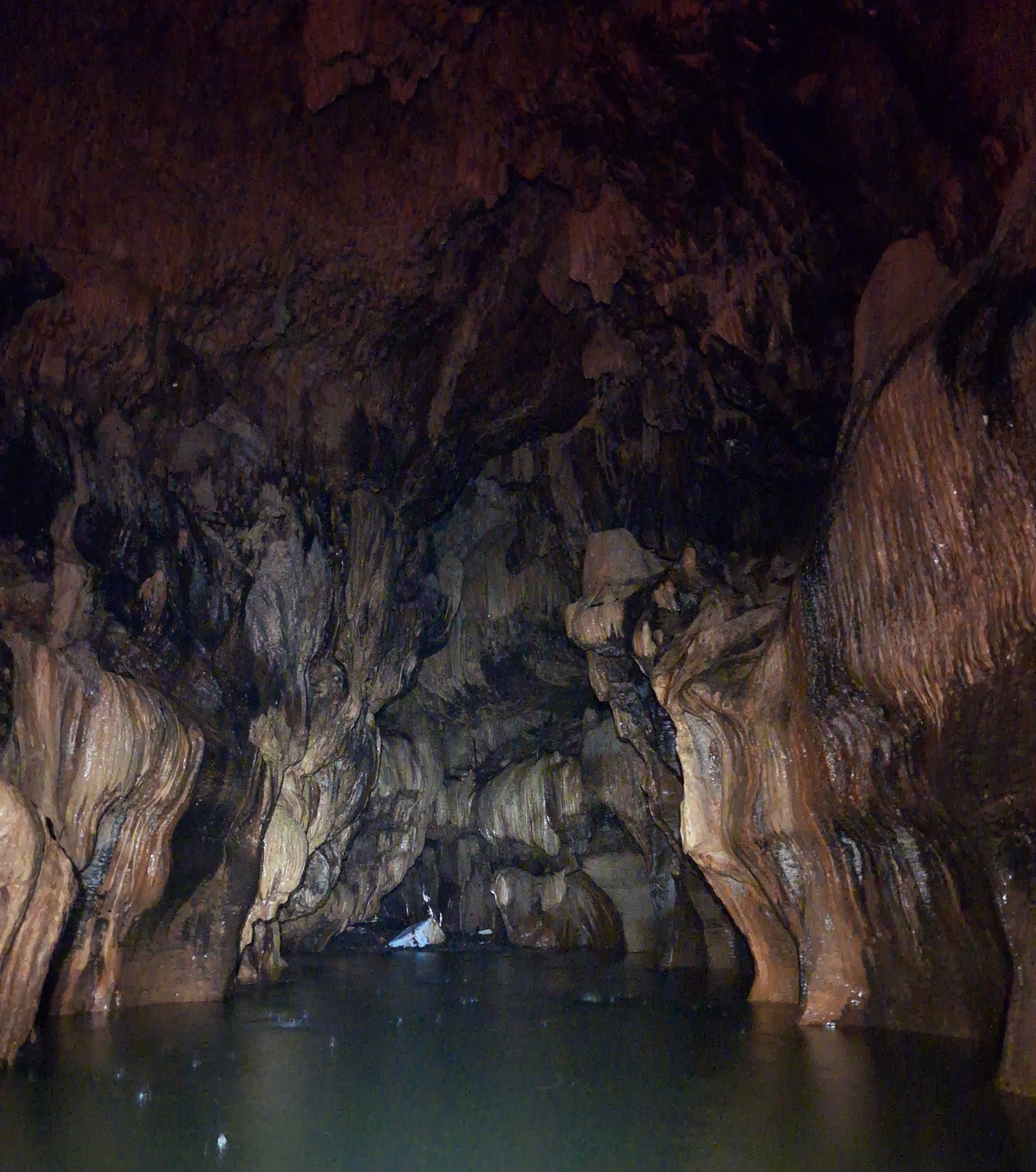 Glowing cave chamber with stalactites rising from still water