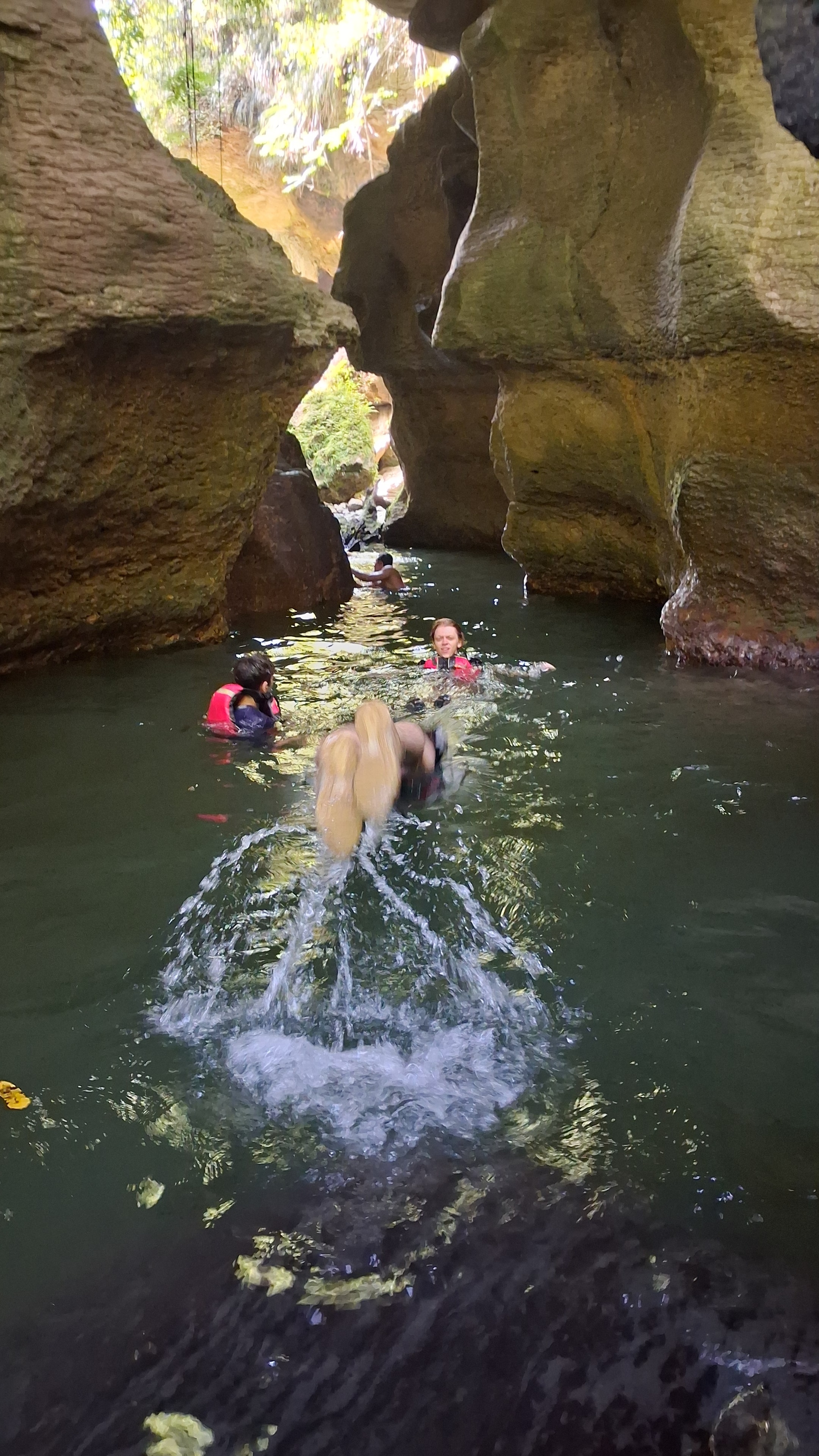 Group climbing limestone rock formations inside the cave with headlamps