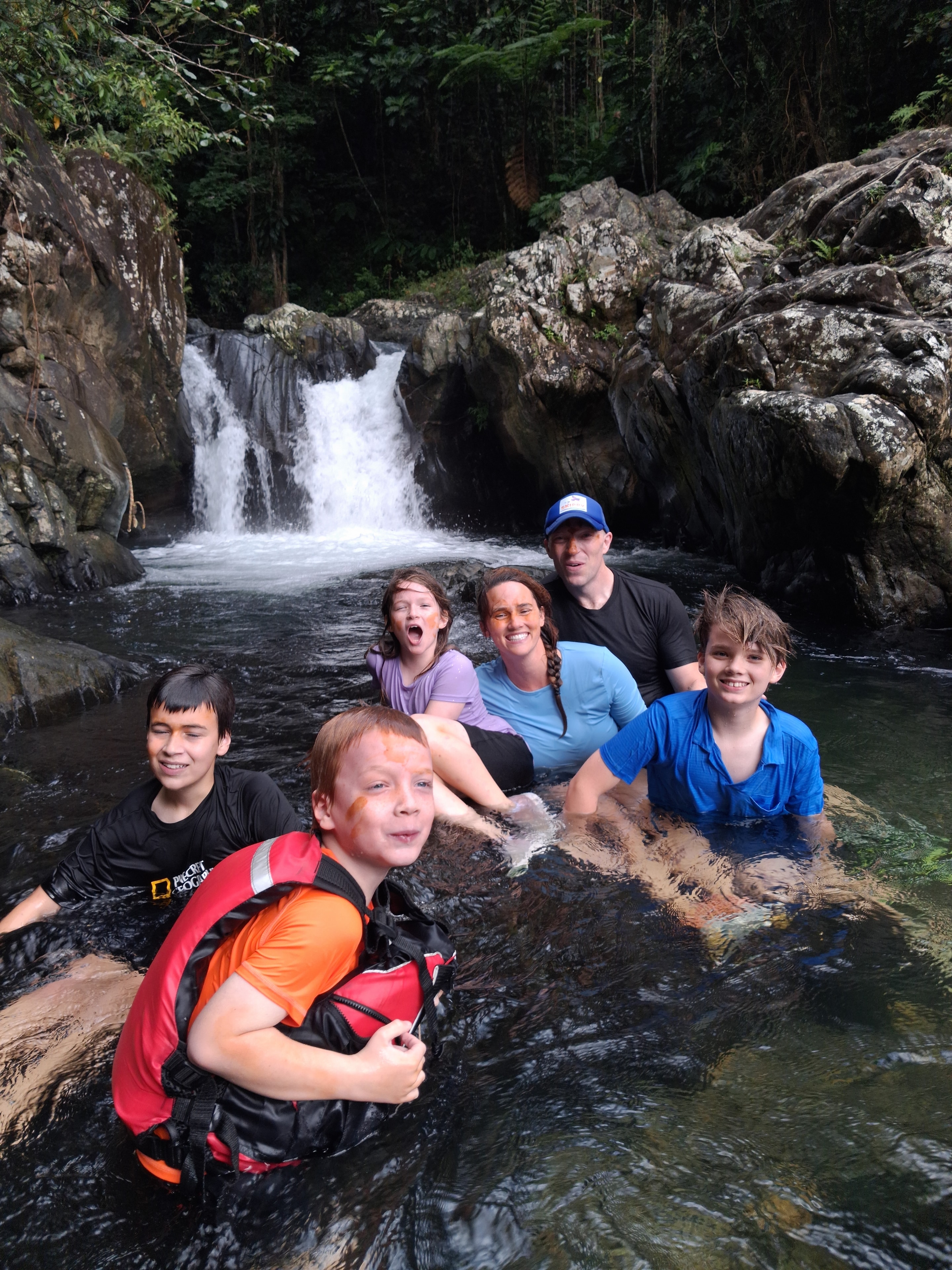 Family of six enjoying the waterfall pool in the rainforest
