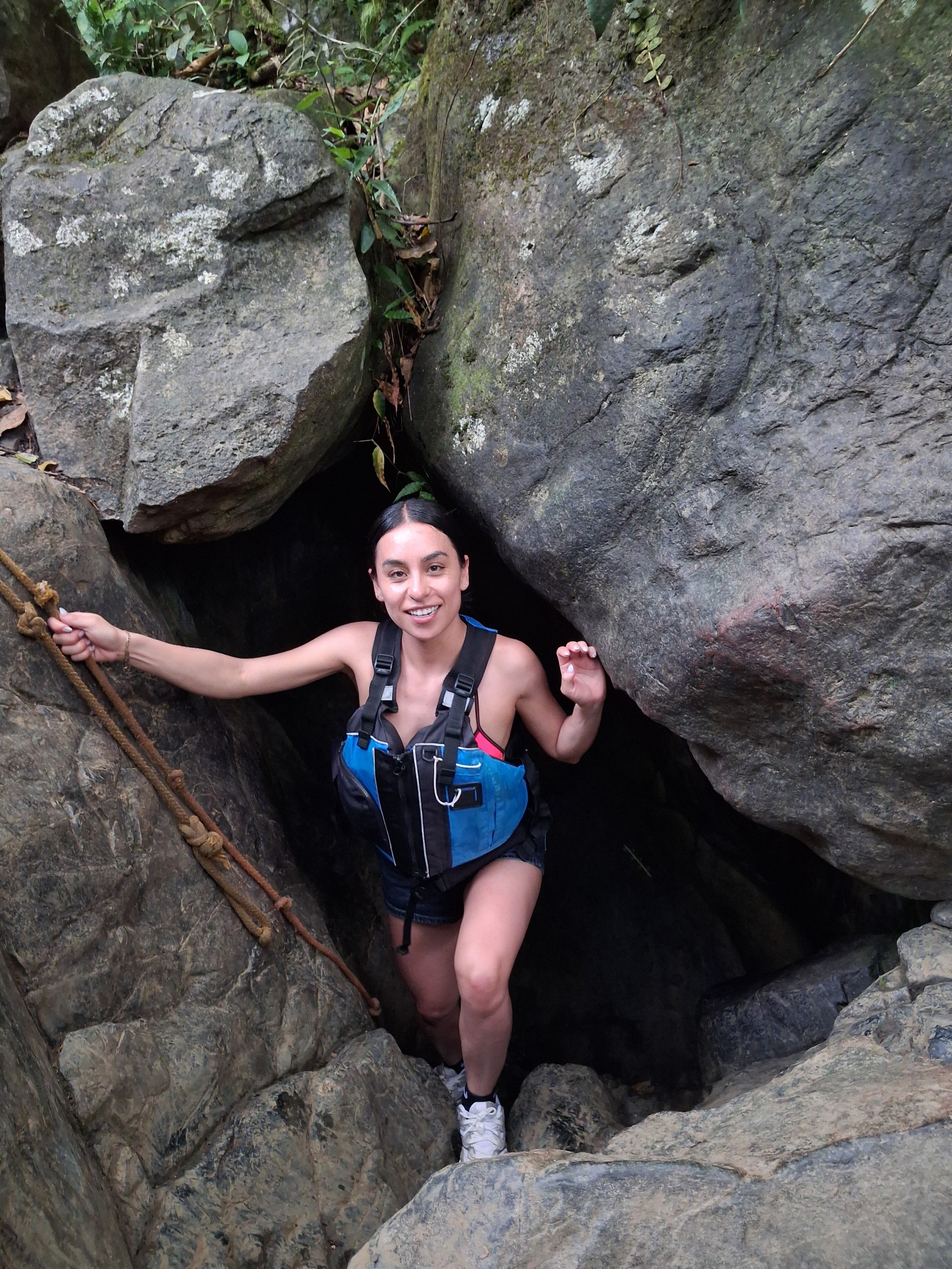 Guest climbing through a rock passage in the rainforest